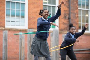 Image of twp Year 5 girls playing with hula hoops in the playground.