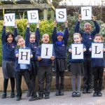 Image of eight children are standing in the playground holding up the letters for West Hill