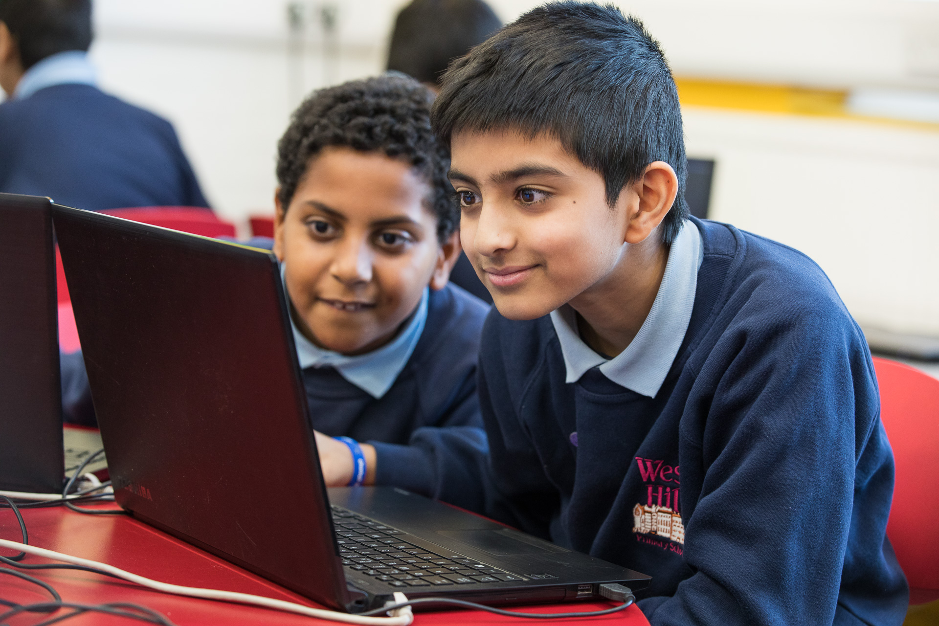 Image of Jaspal and Levi sitting in front of a laptop and working together on a project.