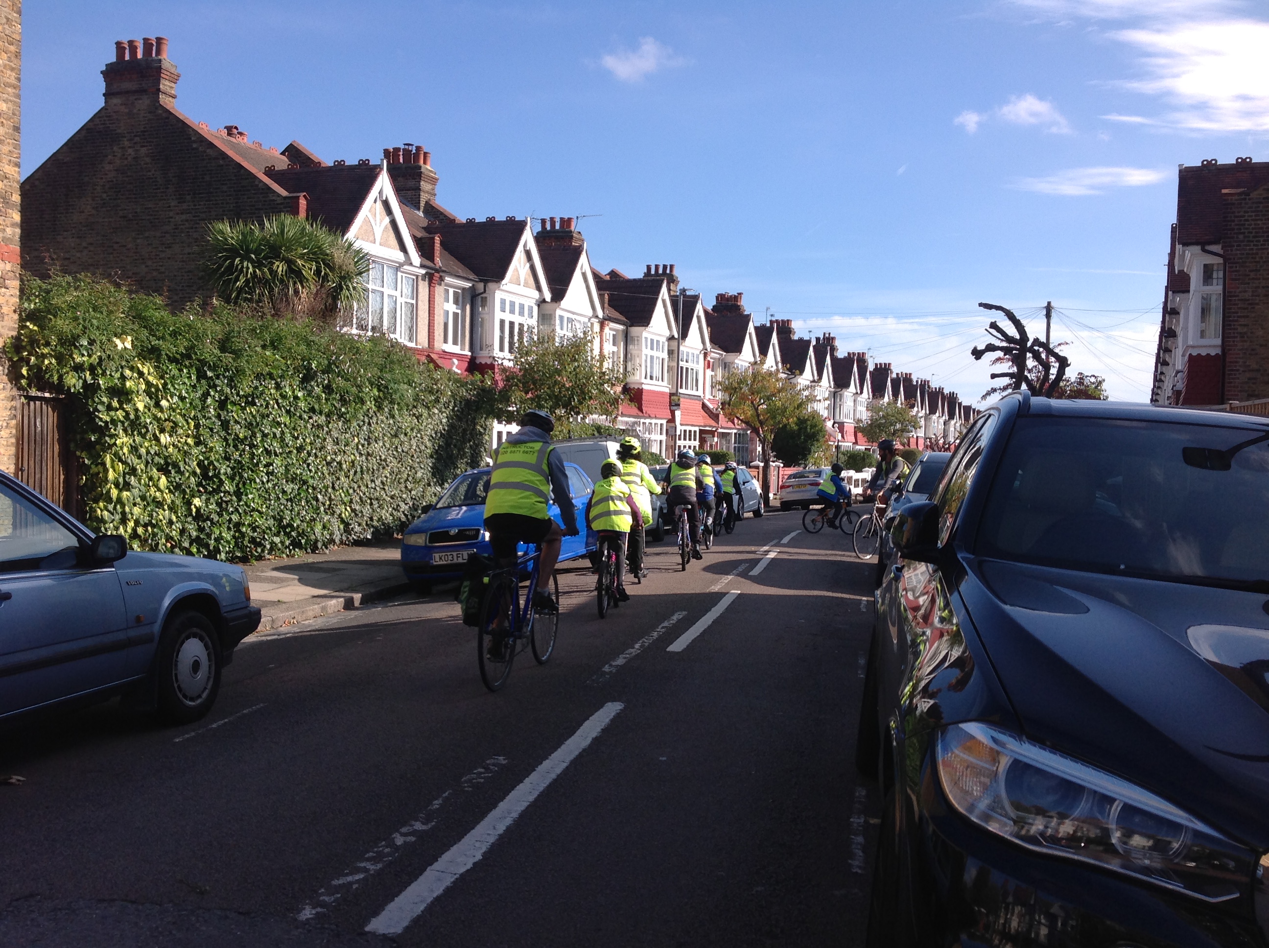 Image of some Year 6 pupils wearing high visibility vests and cycling on the road.