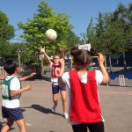 Image of some children are playing netball outside in the playground and are reaching for the ball.