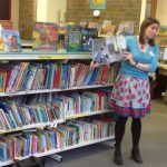 Image of a librarian reading a picture book to the children