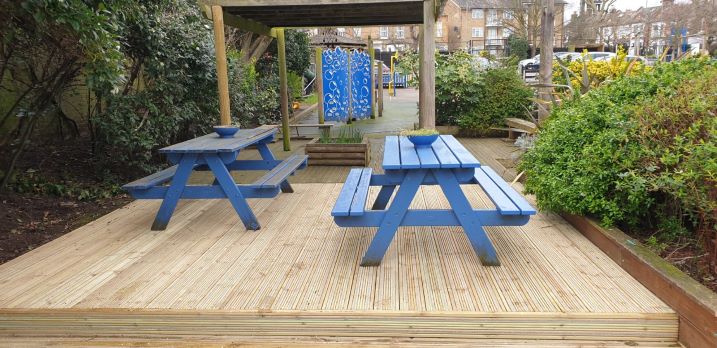Image of decking area in playground with picnic benches on it